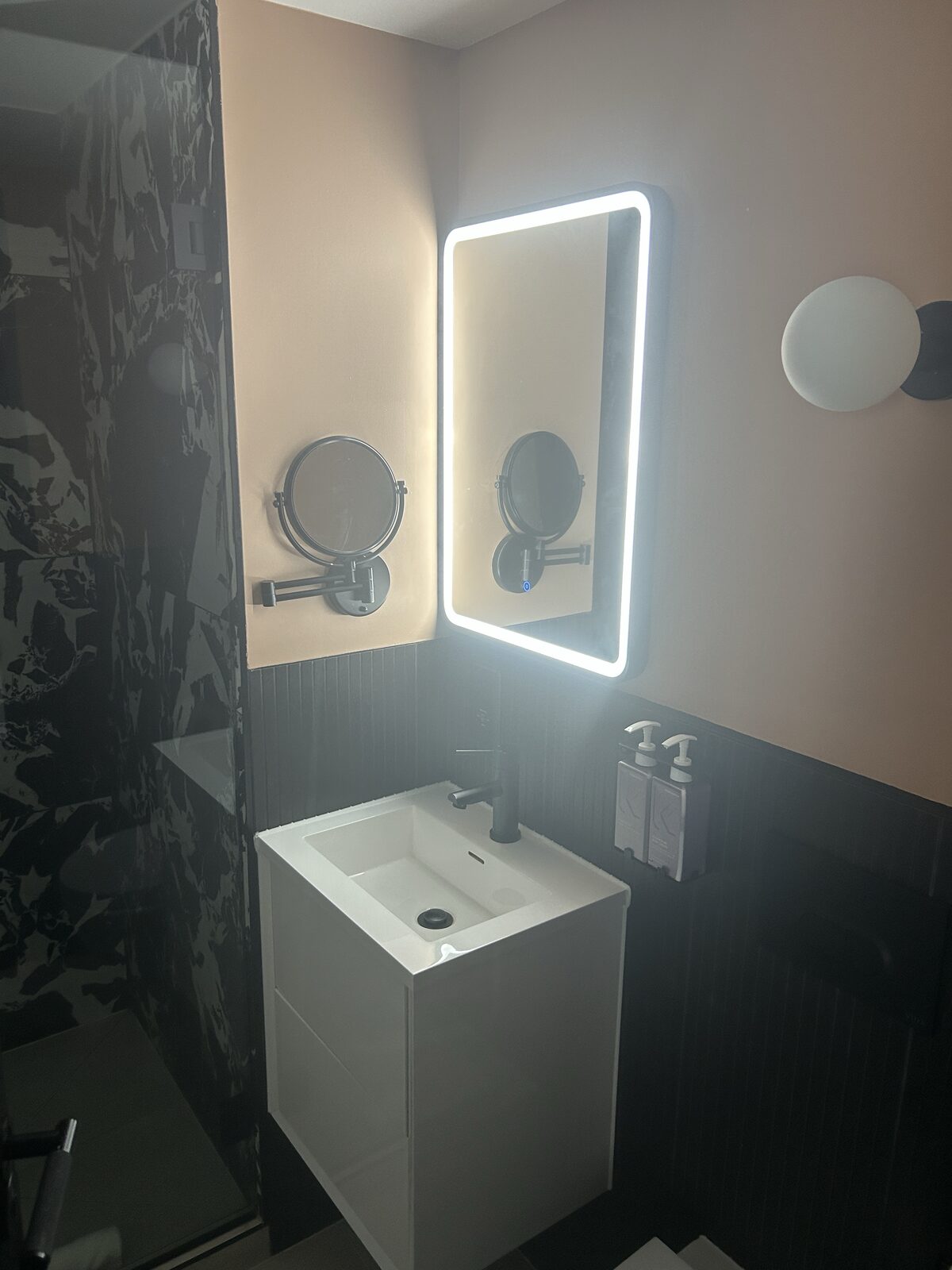 Tribe Hotel bathroom with LED backlit mirror and marble-effect tiles